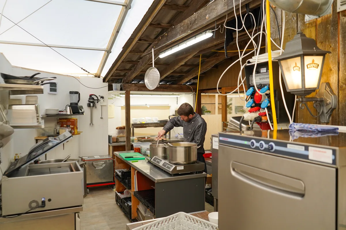 Man sieht eine Gastronomieküche und einen Koch.